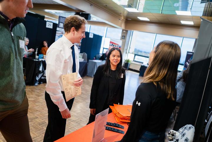 three students at career fair talking to a recruiter